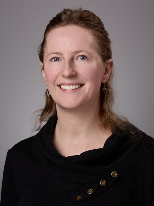 Headshot of woman with light red hair wearing black sweater.