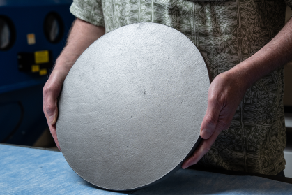 Man's hands holding a round piece of cermet