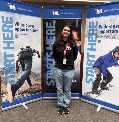 Female engineering student stands in front of banners that say Start Here.